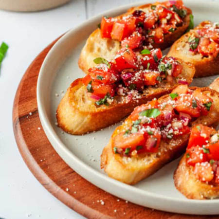 Bruschetta with mozzarella topped with diced tomatoes, fresh basil, and balsamic glaze.