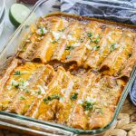 Enchilada recipe featuring rolled tortillas filled with chicken, topped with sauce and cheese in a baking dish.