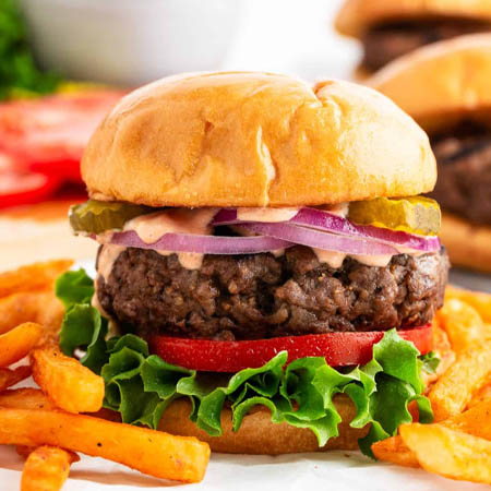 Hamburger recipes featuring a classic beef patty with lettuce, tomato, cheese, and pickles on a toasted bun.