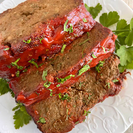 A perfectly baked Lipton meatloaf topped with ketchup glaze, served with mashed potatoes and green beans.