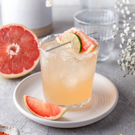 Paloma recipe featuring a refreshing tequila cocktail with grapefruit soda and lime served in a salted glass.