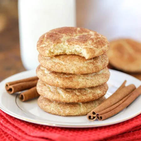 Snickerdoodle recipe featuring soft, chewy cookies rolled in cinnamon-sugar and served on a plate.