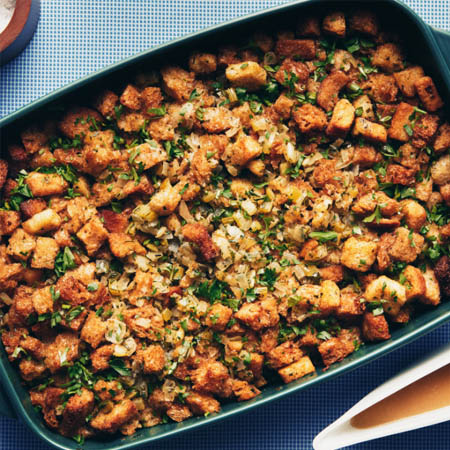 Stuffing recipe featuring cubed bread, onions, celery, and herbs in a baking dish.