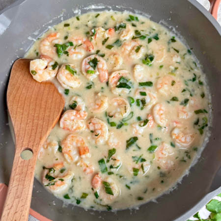 Creamy coconut shrimp recipe featuring shrimp in a coconut milk sauce garnished with lime and cilantro.