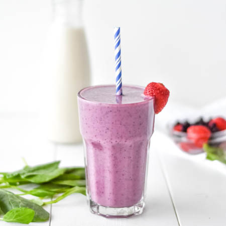 Smoothie recipes featuring a vibrant drink with mixed berries, spinach, and a sprinkle of chia seeds in a glass.