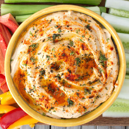 Garlic hummus recipe without tahini served in a bowl, garnished with olive oil, paprika, and parsley.