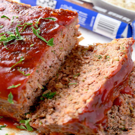 A slice of juicy Lipton Onion Soup Meatloaf served with mashed potatoes and green beans.