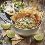 Freshly made guacamole garnished with lime slices and cilantro.