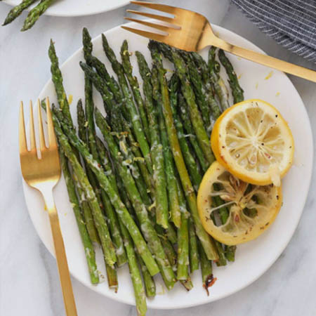 Asparagus recipes featuring roasted asparagus spears garnished with Parmesan and lemon zest on a baking sheet.