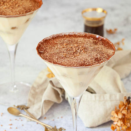 Tiramisu martini recipe featuring a creamy cocktail garnished with cocoa powder and chocolate shavings.