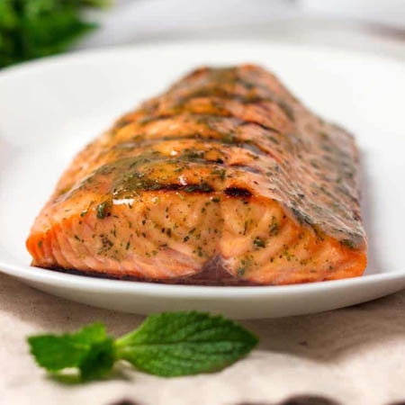 Wilderness salmon recipe featuring fresh salmon fillets cooked with lemon slices and fresh dill on foil.